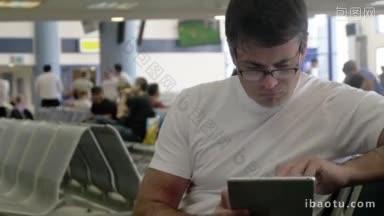 在<strong>机场</strong>或车站候机室，拿着平板电脑的年轻严肃男子正在用平板电脑工作或通过